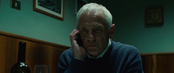 Movie still from “The American” (2010), directed by Anton Corbijn – An older man talking on a cell phone; Close Up shot, Low angle