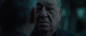 Movie still from “The American” (2010), directed by Anton Corbijn – An old man with a sad look on his face; Close Up shot, Over the shoulder angle