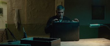 Movie still from “The American” (2010), directed by Anton Corbijn – A man opening up a suitcase on a table; Medium shot, Low angle