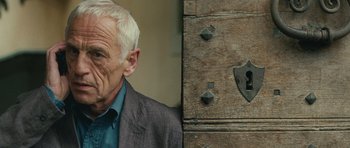 Movie still from “The American” (2010), directed by Anton Corbijn – An older man in a suit standing in front of a wooden door; Close Up shot, Over the shoulder angle