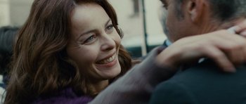 Movie still from “The American” (2010), directed by Anton Corbijn – A person smiling at the camera; Close Up shot, Over the shoulder angle