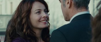 Movie still from “The American” (2010), directed by Anton Corbijn – A man and a woman smiling at each other in front of a building; Close Up shot, Over the shoulder angle