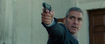 Movie still from “The American” (2010), directed by Anton Corbijn – A man holding a gun in his hand; Close Up shot, Over the shoulder angle