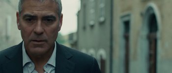 Movie still from “The American” (2010), directed by Anton Corbijn – A person wearing a suit and tie; Close Up shot, Over the shoulder angle