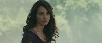 Movie still from “The American” (2010), directed by Anton Corbijn – A beautiful young woman with long brown hair and blue eyes; Close Up shot, Over the shoulder angle