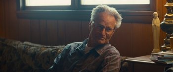 Movie still from “Out of the Furnace” (2013), directed by Scott Cooper – An older man wearing glasses sitting in front of a window; Close Up shot, Over the shoulder angle
