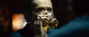 Movie still from “Out of the Furnace” (2013), directed by Scott Cooper – A man drinking a glass of beer from a glass; Close Up shot, Over the shoulder angle