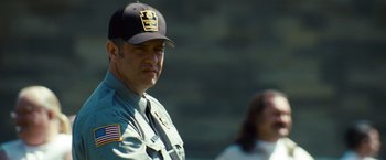 Movie still from “Out of the Furnace” (2013), directed by Scott Cooper – A police officer wearing a hat and a uniform; Close Up shot, Low angle