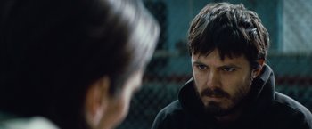 Movie still from “Out of the Furnace” (2013), directed by Scott Cooper – A man with a beard is looking at another man; Close Up shot, Over the shoulder angle