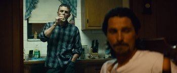 Movie still from “Out of the Furnace” (2013), directed by Scott Cooper – Two men sitting in a kitchen drinking coffee; Medium shot, Over the shoulder angle