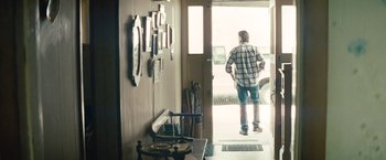 Movie still from “Out of the Furnace” (2013), directed by Scott Cooper – A man standing in front of an open front door; Wide shot, Over the shoulder angle