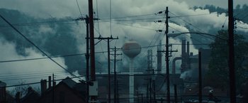 Movie still from “Out of the Furnace” (2013), directed by Scott Cooper – A view of power lines , a water tower and a factory; Extreme Wide shot, Low angle