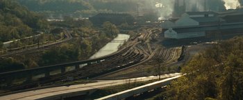 Movie still from “Out of the Furnace” (2013), directed by Scott Cooper – A view of a train yard from a hill; Extreme Wide shot, High angle