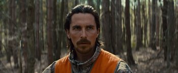 Movie still from “Out of the Furnace” (2013), directed by Scott Cooper – A person with long hair wearing a vest; Close Up shot, Over the shoulder angle