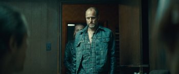 Movie still from “Out of the Furnace” (2013), directed by Scott Cooper – A man standing next to another man in a doorway; Medium shot, Low angle