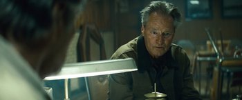 Movie still from “Out of the Furnace” (2013), directed by Scott Cooper – An older man sitting in front of a lamp; Close Up shot, Low angle