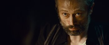 Movie still from “Out of the Furnace” (2013), directed by Scott Cooper – A person with a beard looking at the camera; Close Up shot, Low angle