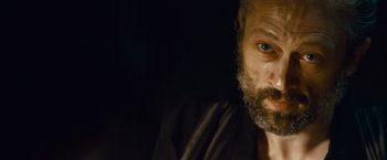 Movie still from “Out of the Furnace” (2013), directed by Scott Cooper – A person with a beard looking at the camera; Close Up shot, Over the shoulder angle