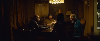 Movie still from “Out of the Furnace” (2013), directed by Scott Cooper – A group of people sitting around a table; Medium shot, Over the shoulder angle