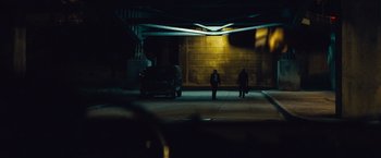 Movie still from “Out of the Furnace” (2013), directed by Scott Cooper – Two people standing in a parking garage at night; Extreme Wide shot, Low angle