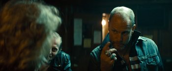 Movie still from “Out of the Furnace” (2013), directed by Scott Cooper – A man smoking a cigarette while sitting next to another man; Close Up shot, Over the shoulder angle