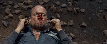 Movie still from “Out of the Furnace” (2013), directed by Scott Cooper – A man with a bloody face and a tattoo on his arm; Close Up shot, Overhead angle