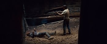 Movie still from “Out of the Furnace” (2013), directed by Scott Cooper – A man standing next to a man laying on the ground; Wide shot, High angle