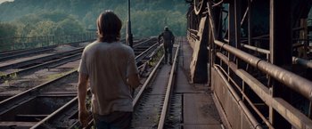Movie still from “Out of the Furnace” (2013), directed by Scott Cooper – Two people are walking along the railroad tracks; Wide shot, Over the shoulder angle