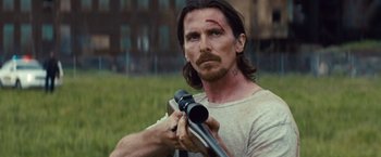 Movie still from “Out of the Furnace” (2013), directed by Scott Cooper – A person holding a rifle; Close Up shot, Over the shoulder angle
