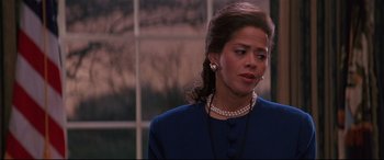 Movie still from “The American President” (1995), directed by Rob Reiner – A person wearing a suit and a pearl necklace; Close Up shot, Over the shoulder angle