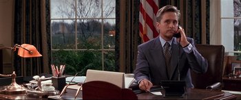 Movie still from “The American President” (1995), directed by Rob Reiner – A man sitting at a desk in front of an american flag; Medium shot, Low angle
