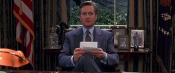 Movie still from “The American President” (1995), directed by Rob Reiner – A man sitting in a chair holding an envelope in his hands; Medium shot, Low angle