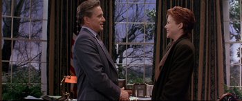 Movie still from “The American President” (1995), directed by Rob Reiner – A man and a woman standing next to each other in front of an american flag; Medium shot, Over the shoulder angle