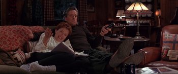 Movie still from “The American President” (1995), directed by Rob Reiner – A man and a woman sitting on a couch with a remote; Medium shot, Low angle