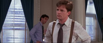 Movie still from “The American President” (1995), directed by Rob Reiner – A man wearing a tie and suspenders in front of another man; Medium shot, Over the shoulder angle