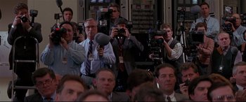 Movie still from “The American President” (1995), directed by Rob Reiner – A group of people taking pictures in a room; Medium shot, High angle