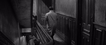 Movie still from “The Apartment” (1960), directed by Billy Wilder – A black and white photo of a man walking down stairs; Wide shot, High angle