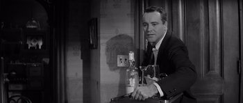 Movie still from “The Apartment” (1960), directed by Billy Wilder – A black and white photo of a man sitting at a table with a glass of wine; Close Up shot, Low angle