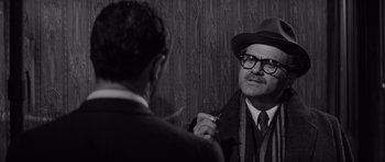 Movie still from “The Apartment” (1960), directed by Billy Wilder – A man in a hat and glasses is talking to another man in a suit and tie; Close Up shot, Over the shoulder angle