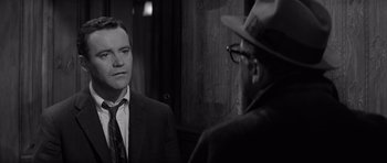 Movie still from “The Apartment” (1960), directed by Billy Wilder – A man wearing a suit and tie talking to another man wearing a hat; Close Up shot, Over the shoulder angle
