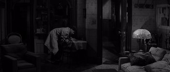 Movie still from “The Apartment” (1960), directed by Billy Wilder – A man leaning over a table in a room; Wide shot, High angle