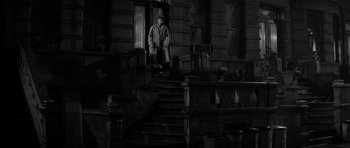 Movie still from “The Apartment” (1960), directed by Billy Wilder – A man standing on the steps of an old building; Wide shot, High angle