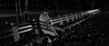 Movie still from “The Apartment” (1960), directed by Billy Wilder – An older man sitting on a bench at night; Wide shot, High angle