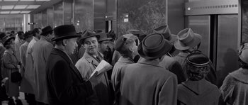 Movie still from “The Apartment” (1960), directed by Billy Wilder – A black and white photo of a group of men wearing hats; Medium shot, High angle