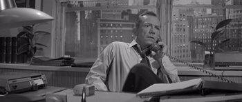 Movie still from “The Apartment” (1960), directed by Billy Wilder – An older man sitting at a desk talking on the phone; Close Up shot, High angle
