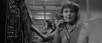 Movie still from “The Apartment” (1960), directed by Billy Wilder – A group of women in a room holding phones; Medium shot, Low angle