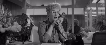 Movie still from “The Apartment” (1960), directed by Billy Wilder – An older woman talking on a phone in an office setting; Close Up shot, Low angle