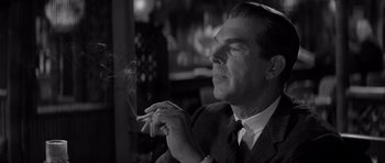 Movie still from “The Apartment” (1960), directed by Billy Wilder – A black and white photo of a man smoking a cigarette; Close Up shot, Low angle