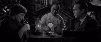 Movie still from “The Apartment” (1960), directed by Billy Wilder – A man sitting at a table with a plate in front of him; Medium shot, Over the shoulder angle