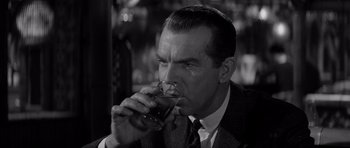 Movie still from “The Apartment” (1960), directed by Billy Wilder – A black and white photo of a man drinking a glass of wine; Close Up shot, Over the shoulder angle